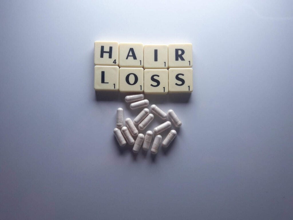 HAIR LOSS 글자 타일과 흰색 캡슐 알약이 놓인 모습, 탈모를 부르는 생활 습관 7가지 글 대표 이미지
